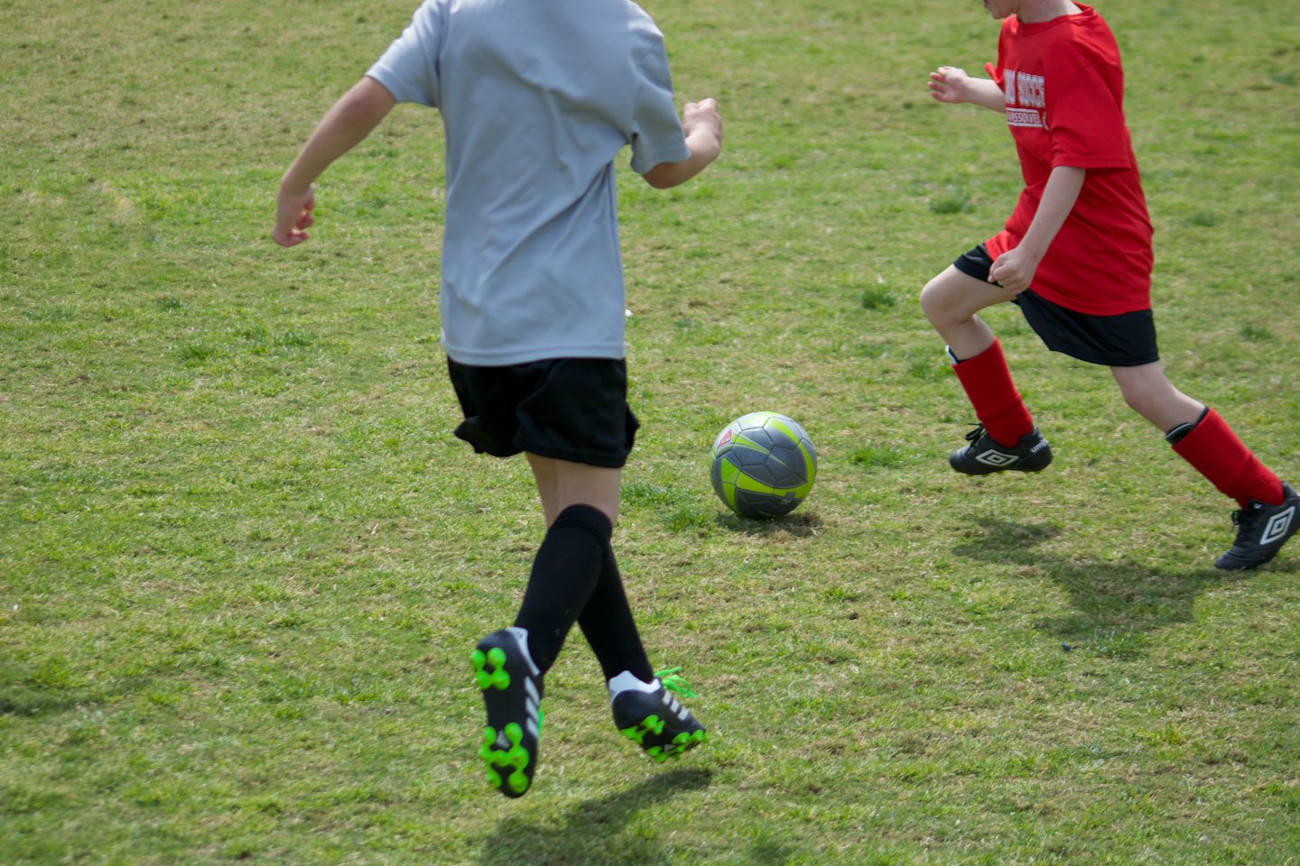 Due bambini giocano a calcio su un prato verde brillante.